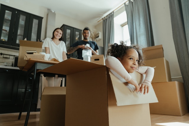 A kid in a card box in home.