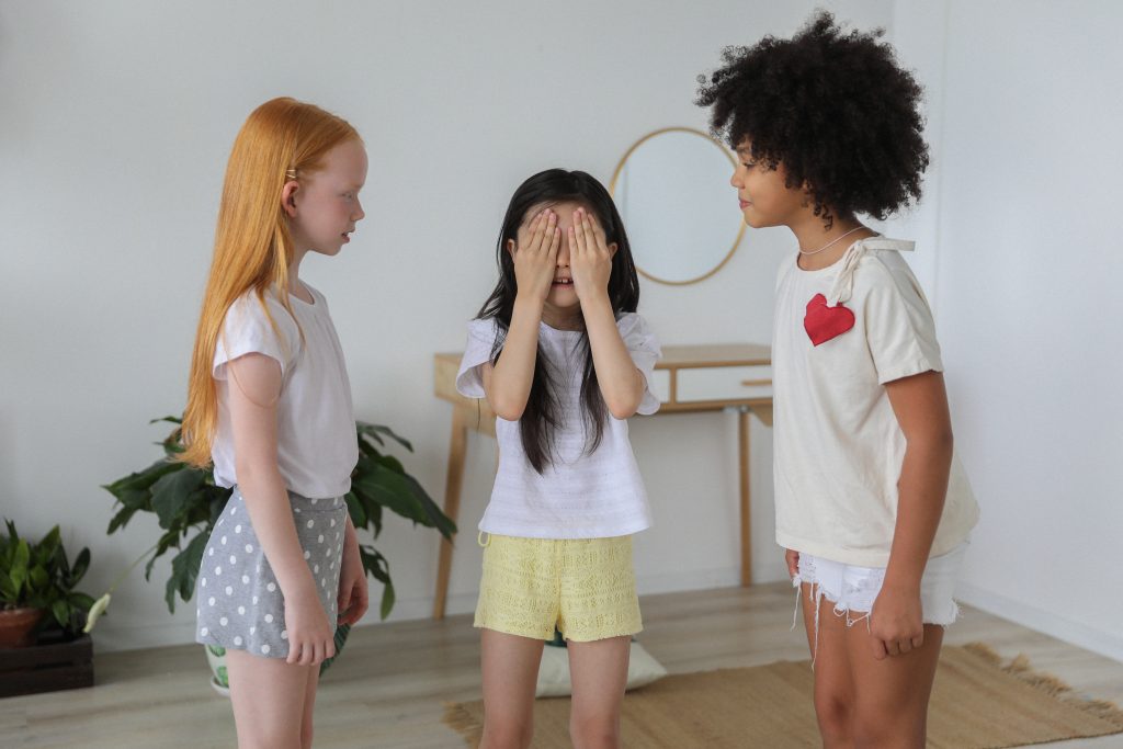 Three kids playing hide and seek.