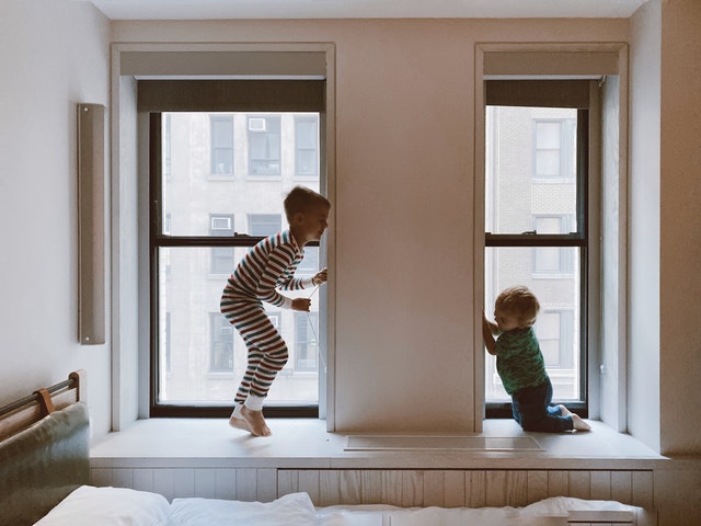 Two kids p[laying beside glass windows.