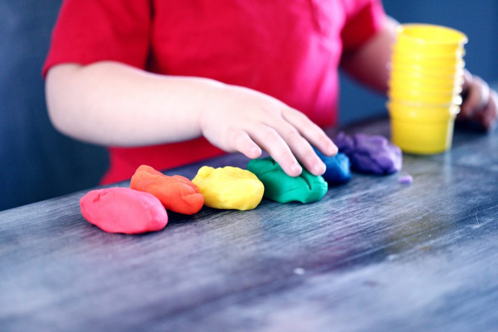 A kid is making figures out of play dough.